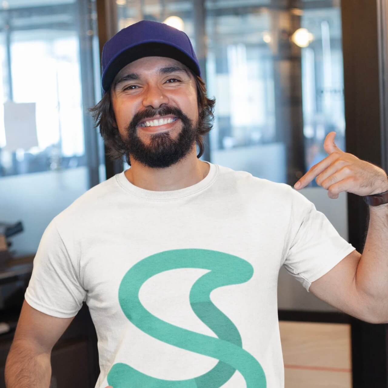 Membro del team che sorride e indica con i pollici il logo “S” di Simple Budget Excel sulla maglietta. Immagine di branding positivo e coinvolgimento del team.